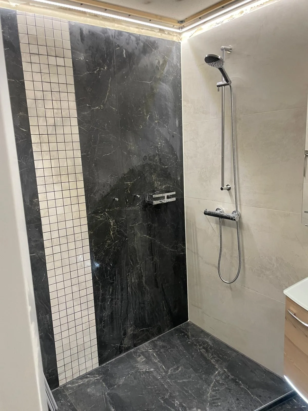 Dusche mit schwarzen Armaturen und Mosaikdetail